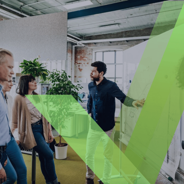 Team gathered around a presenter in a modern office setting - square image